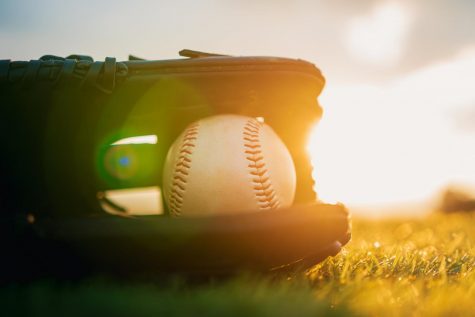 Baseball in glove in the lawn at sunset in the evening day with sun ray and lens flare light.