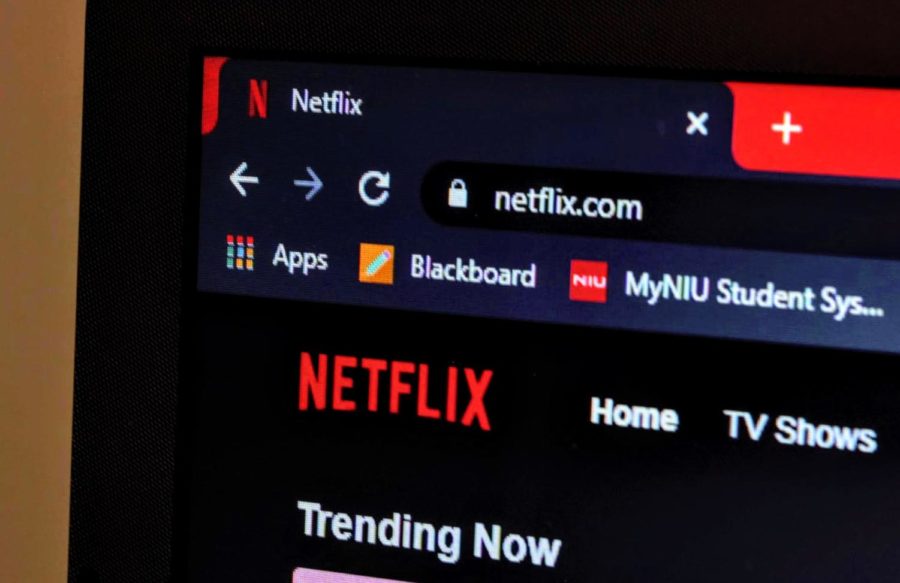 The Netflix home page shows a list of trending shows on a laptop screen. 