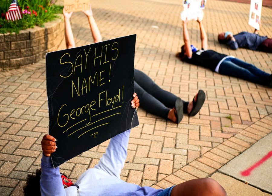 A DeKalb protester holds a Say his name! George Floyd sign in Summer 2020.