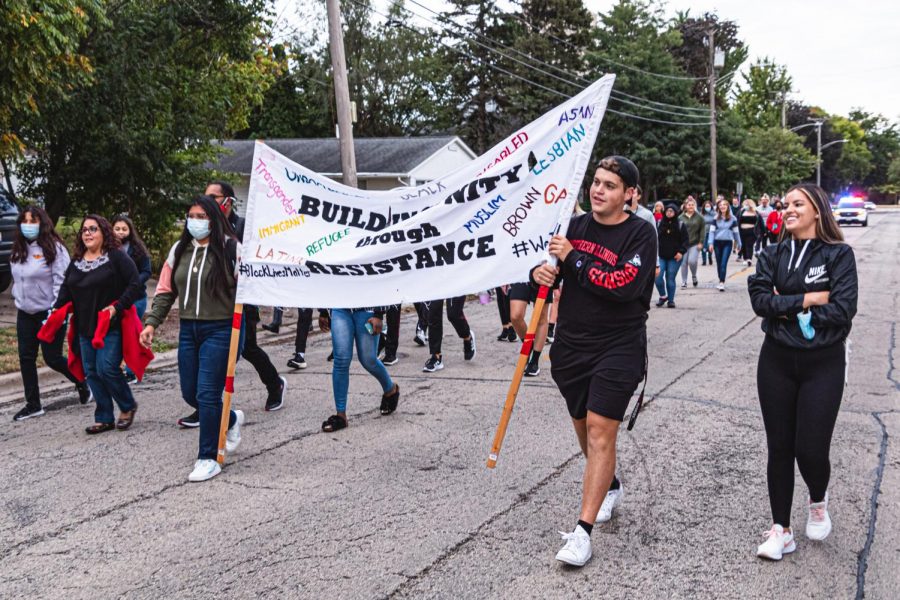 Students participating in Tuesdays Unity Walk with a sign that reads Building unity through resistance. 
