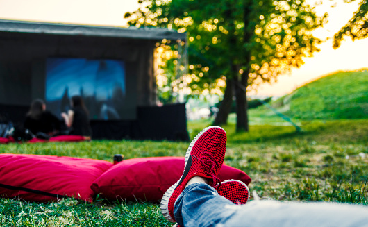 Person watches movie in open cinema in green nature.