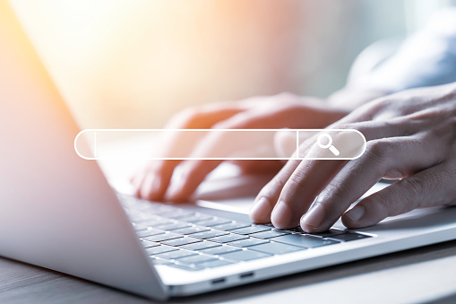Person uses laptop computer to input keyword for search.