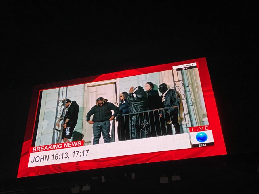 Assortment of rappers and musicians accompanying Kanye West on the porch of his recreated childhood home. 