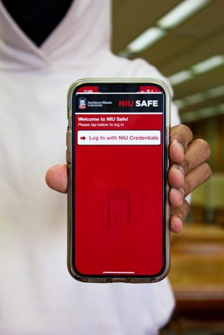 A student holding a phone with the NIU Safe App. 