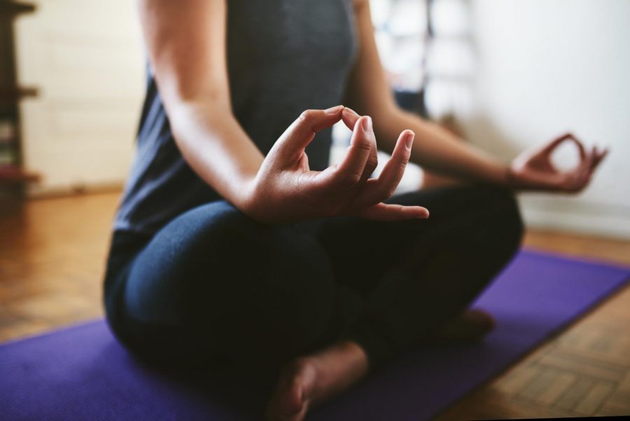 Woman sitting on a yoga mat and meditating alone in her home.