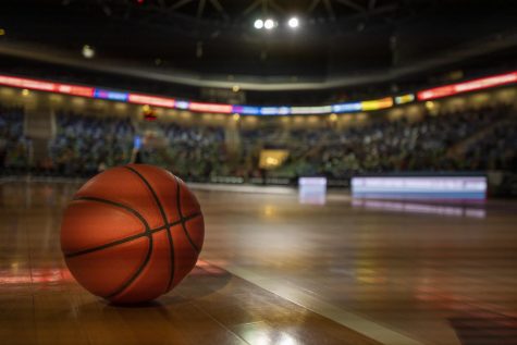 A basketball sits on the court of a large stadium.