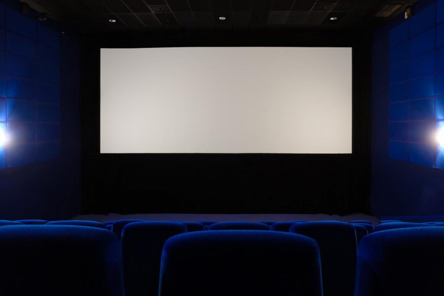 Empty cinema hall. View of empty white cinema screen from the upper rows of the auditorium.
