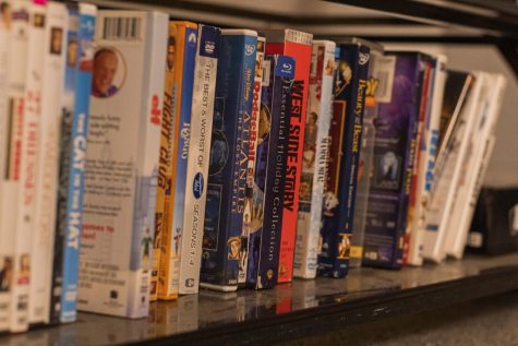 Movie cases line up on a dusty shelf in a college apartment. Physical copies have gone ancient due to streaming services taking off.  
