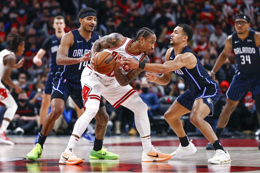 Chicago Bulls forward DeMar DeRozan, center, is defended by Orlando Magic guard Gary Harris, left, and guard Jalen Suggs, right, during the second half of an NBA basketball game, Tuesday, Feb. 1, 2022, in Chicago. (AP Photo/Kamil Krzaczynski)