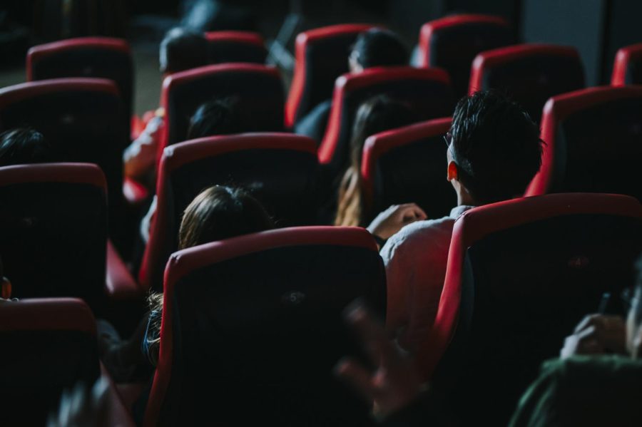 An audience sits in a theater, watching a movie. There are have been films featuring the iconic Batman character.