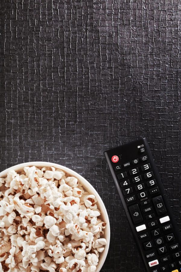 Bowl of popcorn with TV remote control on a black textured background (Getty Images)