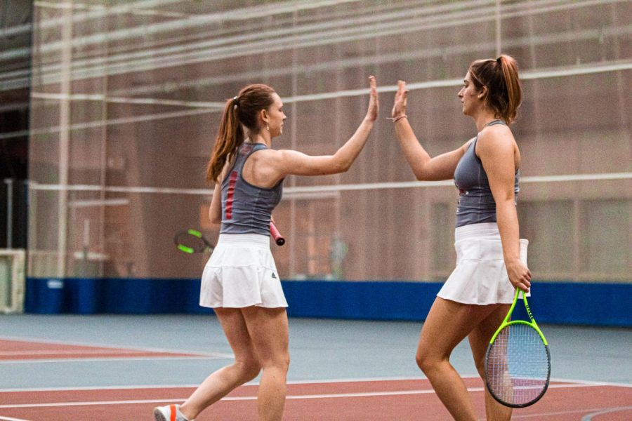 Sophomore Diana Lukyanova and freshman Reagan Welch high-five during a tennis match.