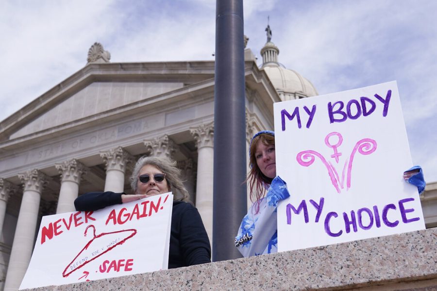 Dani Thayer, left, and Marina Lanae, right, both of Tulsa, Okla., hold pro-choice signs at the state Capitol, Wednesday, April 13, 2022, in Oklahoma City, the day after Oklahoma Gov. Kevin Stitt signed into law a bill making it a felony to perform an abortion, punishable by up to 10 years in prison. 
