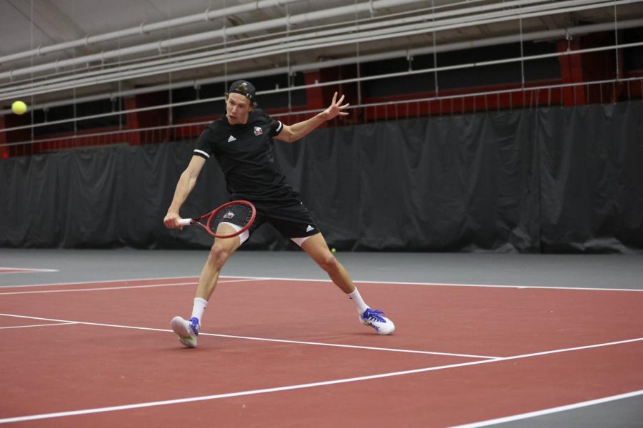 Sophomore Mikael Vollbach hits a tennis ball with a back-hand swing during a match against Binghamton University April 1 in DeKalb.