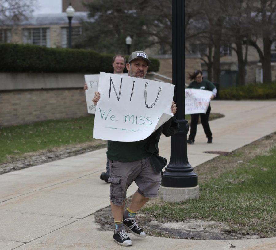 NIU non-tenured English instructor Dan Libman, walks with a sign saying "NIU we miss you" during Wednesday's IFT and UPI informational picket outside of Altgeld Hall. Libman has been an instructor since 1998 and said he's never seen the university walk away from the bargaining table until this go around.The picket comes after university officials walked away from non-tenure negotiations and have refused to begin tenure contract negotiations. (Wes Sanderson | Northern Star)