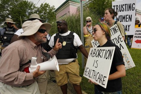A Mississippi clinic security officer (right) attempts to keep anti-abortion activist Doug Lane (left) from a physical confrontation with sign carrying abortion rights supporters. The clinic will close after the state law banning abortions take effect Thursday. (Rogelio V. Solis | Associated Press)