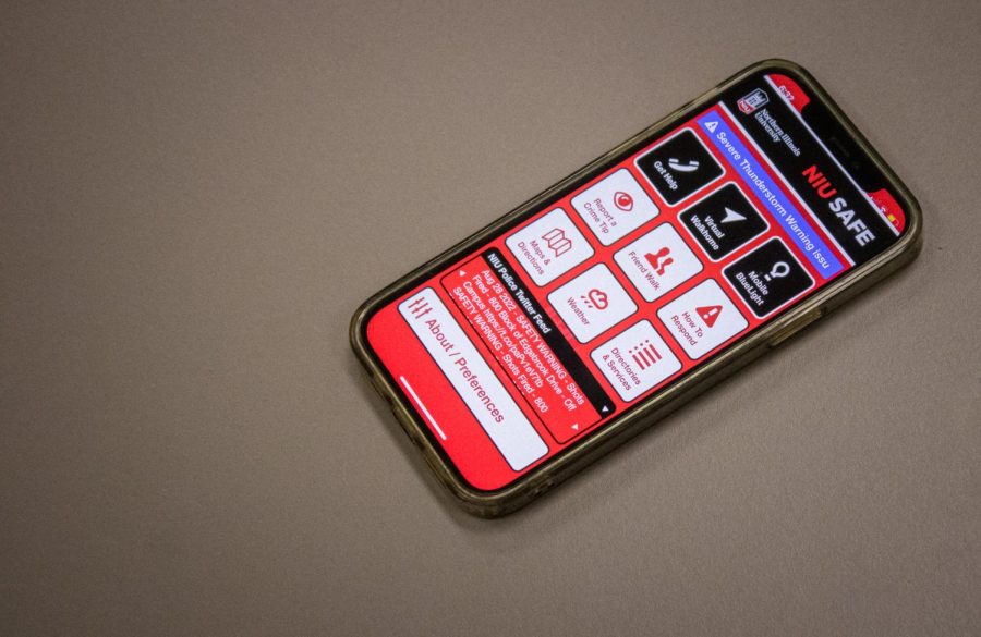 Cell phone resting on a table, open to the home page of the NIU Safe app.