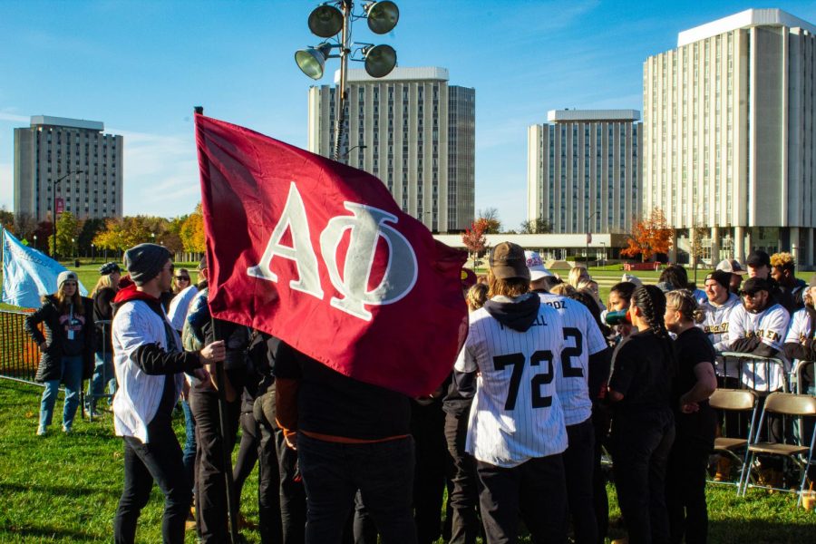 Alpha Phi’s flag bearer Jay Mueller waving the sorority’s flag as the team discusses  winning the first of three total rounds against Alpha Sigma Alpha during Wednesday’s women’s tugs match on campus. (Sean Reed | Northern Star)