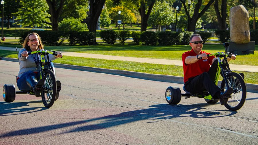 Two participants in the Huskie Trike Race ride down the street Wednesday afternoon on Castle Drive. (Abbi Sweeney | Northern Star)