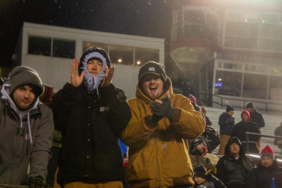 Fans dressed for the snowy weather cheer on the Huskies during  the second quarter of the team’s Wednesday football game against Miami University. (Mingda Wu | Northern Star)