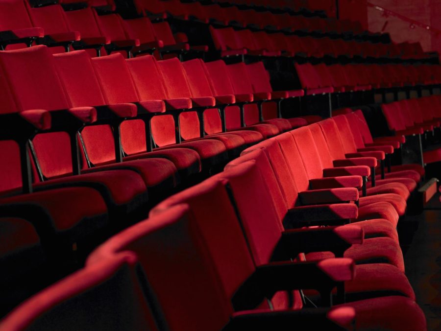 Long curving rows of red theater seats with a dark background. 