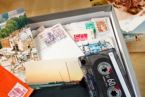 A memory box with letters, a cassette tape and photos used to remember time on a vacation.