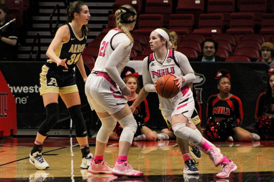 Huskie senior guard Chelby Koker (10) dribbles the ball to an open part of the court while junior forward Tara Stauffacher (21) defends Koker from University of Akron’s sophomore forward Reagan Bass (34) on Wednesday night at the NIU Convocation Center. (Nyla Owens | Northern Star)