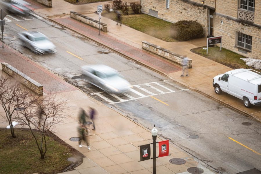 People and cars pass by in the rain on Normal Road Thursday. The exposure was taken from a window on the fourth floor of Founders Memorial Library. (Mingda Wu | Northern Star)