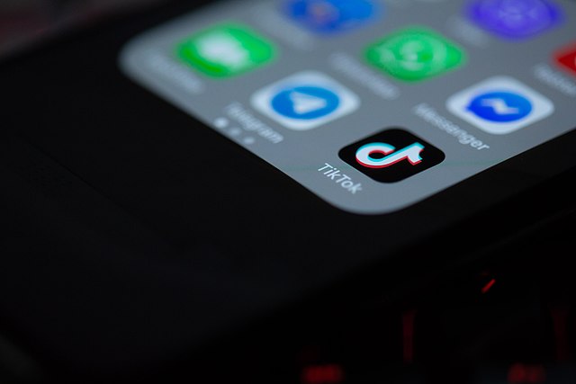 The TikTok logo on a phone screen with other apps around it.