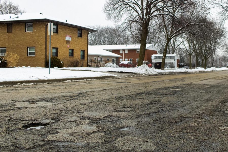 The run-down pavement and potholes of Greenbrier Road filled with melted snow and sleet after a snowstorm in the North Annie Glidden neighborhood. The city is limiting heavy vehicle travel on multiple roads due to deteriorating road conditions. (Sean Reed | Northern Star)