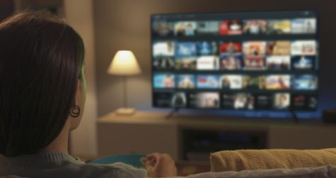 A young woman scrolling through streaming options on her television. Each streaming service has its pros and cons, but which one is the best?