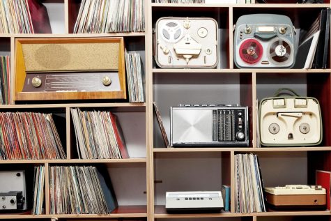 Some vintage radios and stacks of old vinyl records on a wood shelving unit. Albums like Miles Davis’ “Ascenseur Pour L’échafaud” and Lloyd Cole’s “Don’t Get Weird on Me Babe” are perfect for spring listening. 