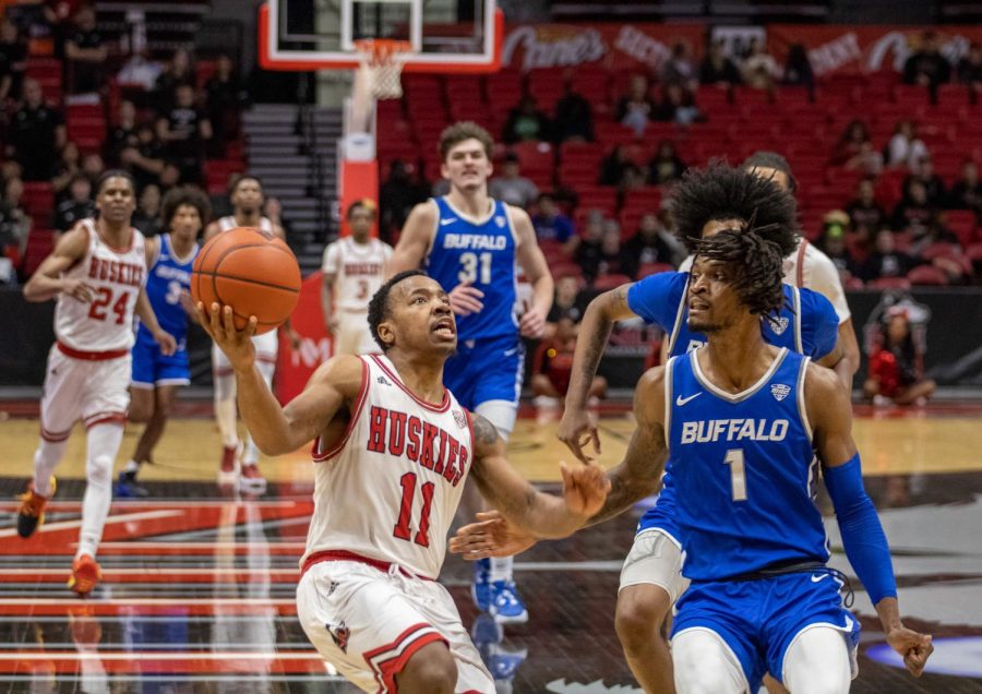 NIU’s sophomore guard David Coit (11) approaching the net and shooting as Buffalo Bulls’ Senior forward, LaQuill Hardnett (1), attempts to catch up and guard Coit during the matchup on Tuesday at the NIU Convocation Center in DeKalb. (Tim Dodge | Northern Star)