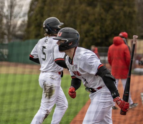 Junior outfielder and catcher Colin Summerhill (8) walks out of the on-deck circle during opening day Friday as junior infielder Eric Erato (5) runs to the dugout. The Huskies lost the game 11-2. (Tim Dodge | Northern Star)