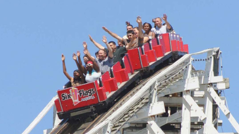 The Six Flags ride The Wild One with riders who have their hands up as it drops over a curve.