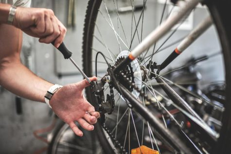 A man fixing the gear shift on the rear wheel of a bike. 
