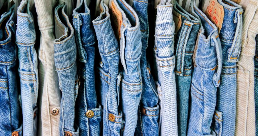 A rack of second hand jeans stacked next to each other. There are many types of denim which are all made to be statement pieces in your wardrobe.