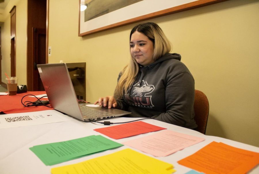 Elizabeth Torres, a junior psychology major, runs one of the check-in tables in the morning Friday at Altgeld Hall, outside the auditorium. (Madelaine Vikse | Northern Star)
