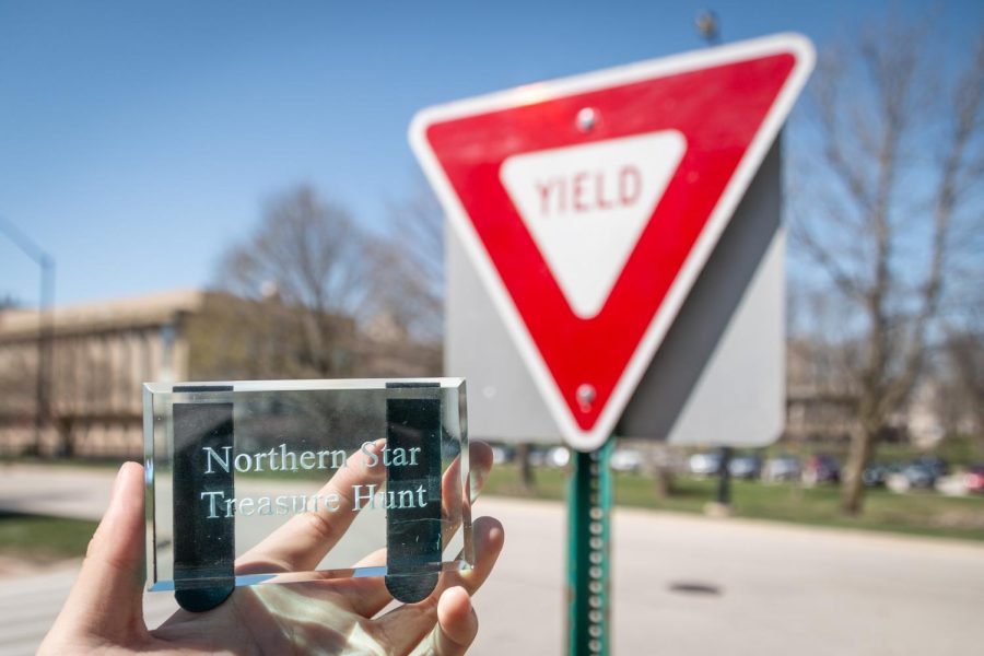 The spot that hides the paperweight for the treasure hunt, in between two signs at Montgomery Hall’s blue parking lot entrance. The 2023 Northern Star Treasure Hunt ended on April 13 as two geology majors found the paperweight that morning. (Mingda Wu | Northern Star)