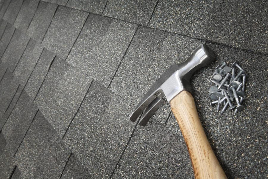 A hammer and nails sitting on a tiled roof. Gov. J.B. Pritzker started a program in parts of Illinois that can provide funding for residential repairs.