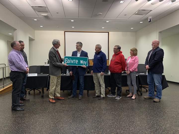 City Manager Bill Nicklas (fourth from left) awards a custom road sign to 7th ward Alderman Anthony Faivre with the City Council surrounding them. Faivre was honored at the Monday City Council meeting for his time as an alderman. (Rachel Cormier | Northern Star)
