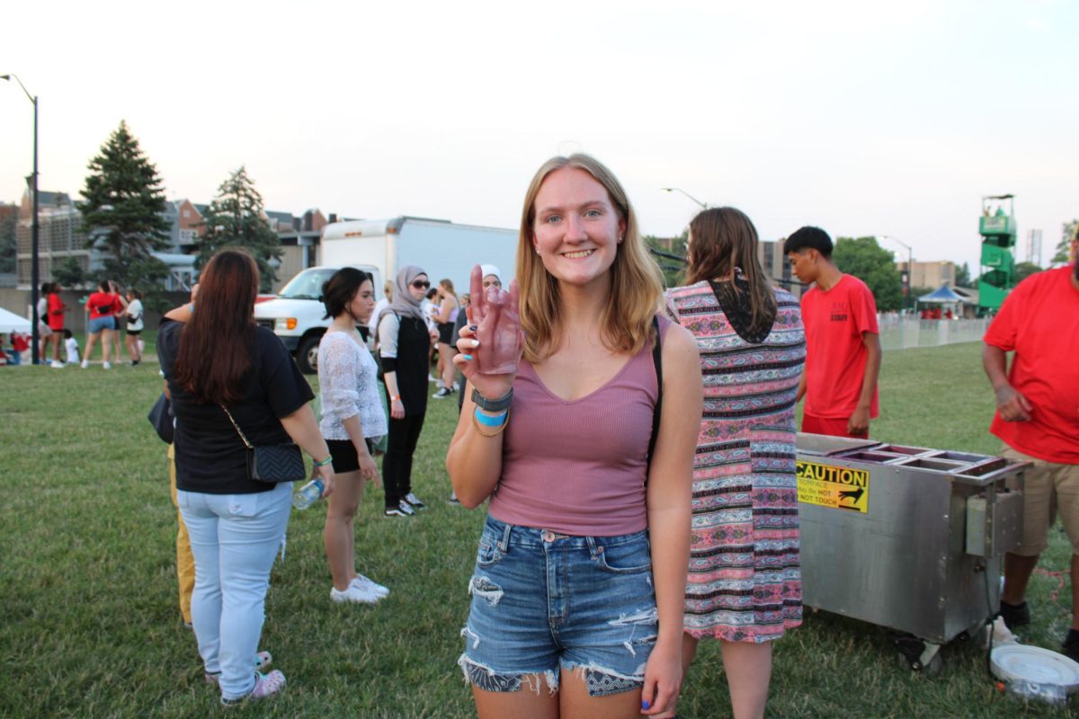  Emma Whitlock, a junior biology environmental studies major, holding a purple wax mold of the Huskie hand symbol during the CAB Block Party on Thursday. Students were asked to dip their hands in hot wax while creating a hand symbol to create molds, then later dipped in their color of choice. (Nyla Owens | Northern Star)

