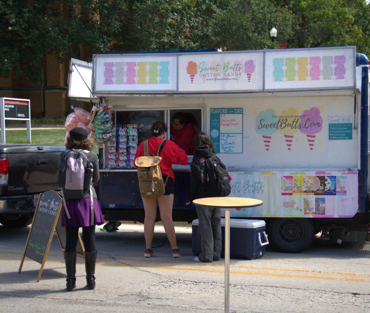 Students gather near Sweet Butts Cotton Candy, the food truck serving cotton candy on Wednesday. The food trucks were located on Normal Road near the Holmes Student Center. 
(Ariyonna McGahee | Northern Star)

