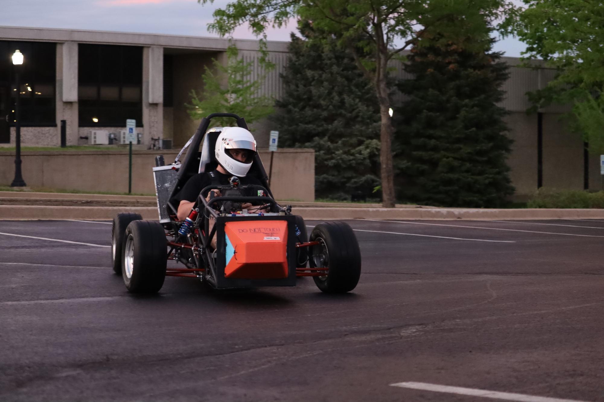 The Huskie Motor Sports club member drives their car in a parking lot. Huskie Motor Sports builds formula SAE cars that they use to compete in events. (Courtesy of Matt Eberle)