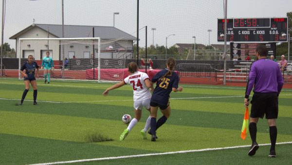 Turf flies out of the ground on Sunday as freshman midfielder Isabel Struble (24) gets ready to kick the ball near the Toledo goal while colliding with Toledo’s senior midfielder Emily Mann (25) attempting to stop the play. (Melody Elbel | Northern Star)
