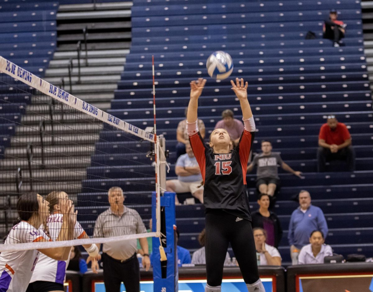 NIU senior setter Ella Mihacevich (15) sets the ball up to her teammate during Friday’s match against the University of Evansville at McGrath-Phillips Arena in Chicago. (Tim Dodge | Northern Star) 

