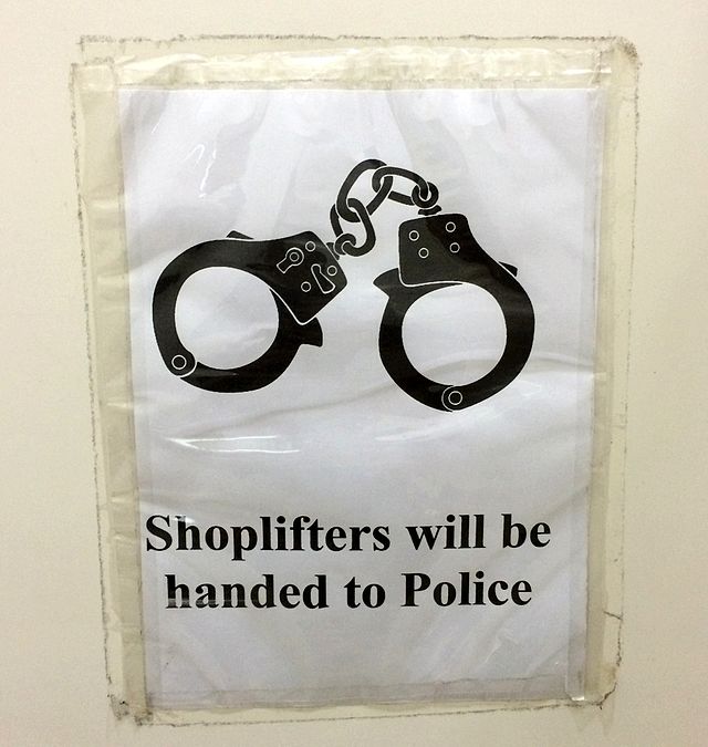 A poster that says Shoplifters will be handed to the Police is taped to a wall. Shoplifting can be a way for poor people to access necessities that they couldnt get otherwise. (Katangais | CCA 2.5)