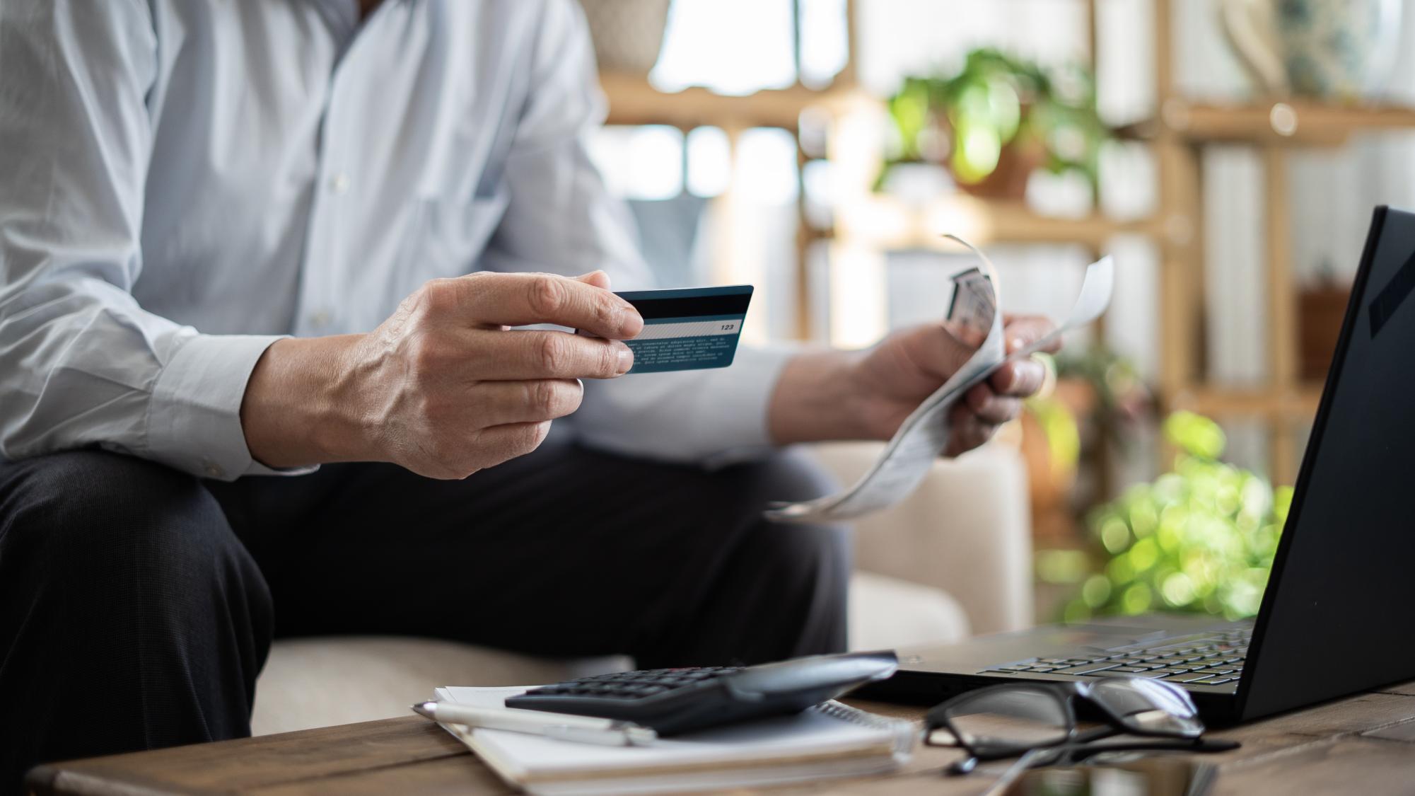 A person holds their card in one hand and papers in the other. Impulsive spending can lead to debt, bad credit and other issues. (Getty Images)