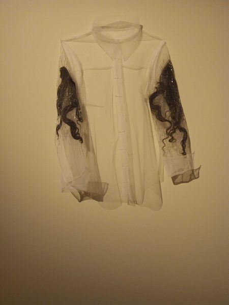 A piece of artwork which shows pieces of hair sewn into a white shirt. This piece is on display in NIUs Altgeld Hall as part of the The Remaining, Mourn... exhibition. (Caleb Johnson | Northern Star)