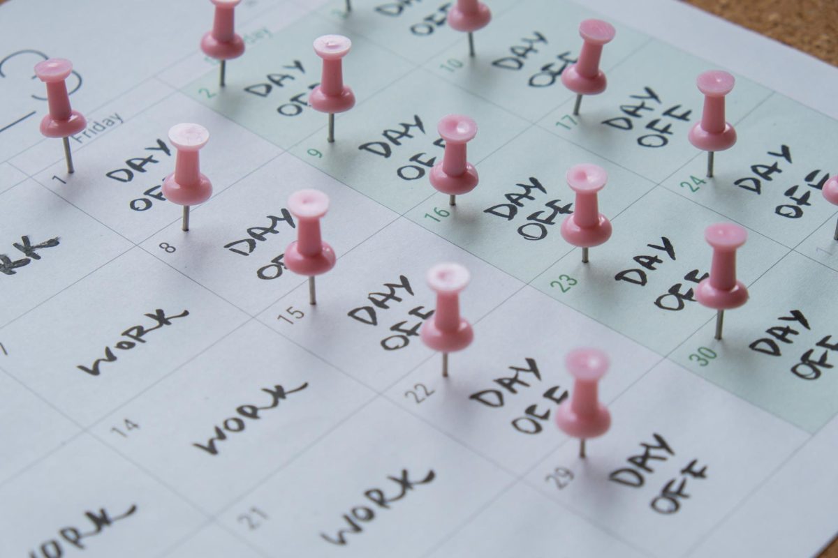 A calendar shows a four-day work week with pink pins pressed on the days off. More businesses and school should implement a four-day week. (Courtesy of Getty Images)